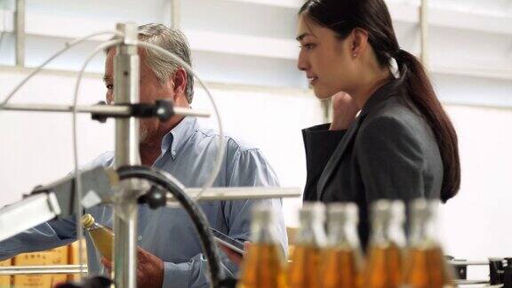 在瓶厂的生产线上高级男女工人在检查瓶子