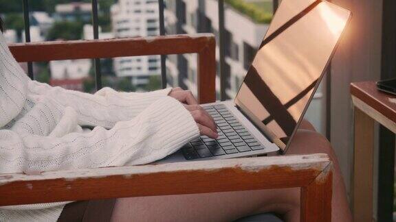 特写亚洲女商人在休闲服装工作在公寓屋顶的笔记本电脑日落