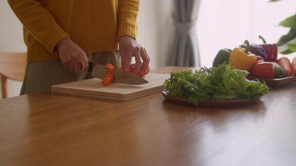 特写的一个女人切胡萝卜在木板上准备食物做沙拉在家里早上