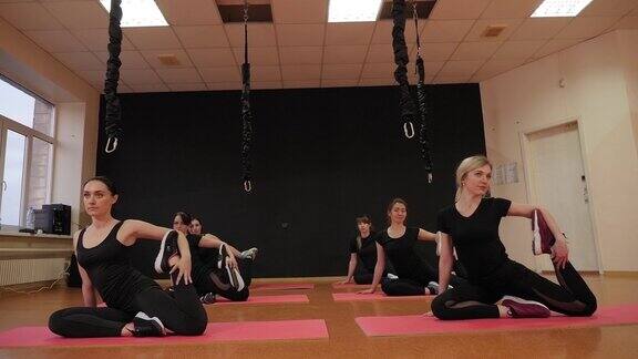 年轻女孩在体育馆的垫子上做运动做伸展运动瑜伽