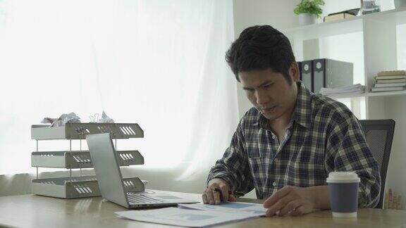 年轻的亚洲商人在家工作在笔记本电脑上计算财务图表数据核对财务文件投资和经营策略并总结成图表