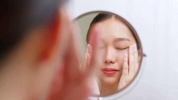 年轻的亚洲美女应用眼霜在健康的面部皮肤亚洲美容皮肤