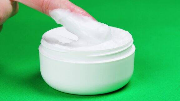 女性手部保湿霜适用于面部或身体绿色背景碗与软奶油特写化妆品质地美容健康护肤理念