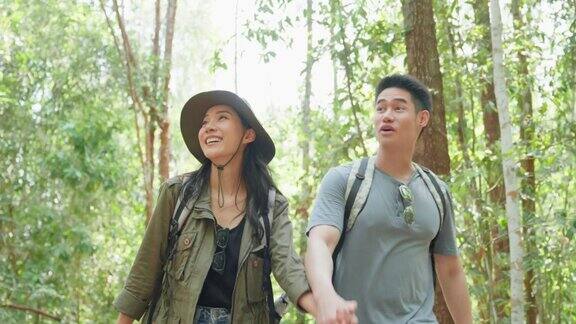 亚洲男人和女人背包客朋友一起在森林里旅行迷人的年轻夫妇在夏天的假期旅行中散步和探索自然木材的幸福和乐趣