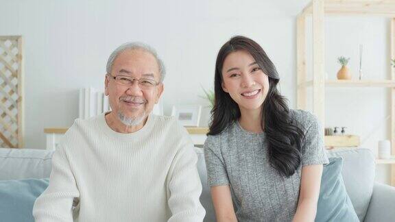 亚洲美女女儿的肖像拥抱和坐在年长的父亲迷人的女人孙女拜访年长的成熟男人在家里享受花时间一起在客厅看着相机