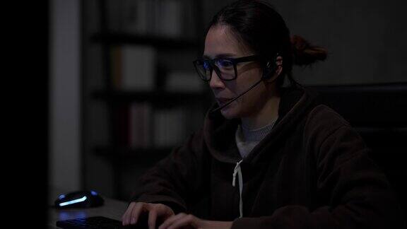 一位年轻的亚洲女性一位软件开发人员坐在一张有多个屏幕的桌子前正在用她的电脑写代码