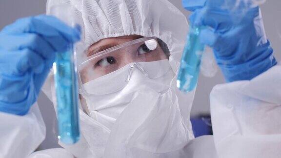 穿着个人防护装备的女科学家在实验室做一些研究检查试管中的液体