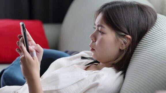 靠近眼睛亚洲女人放松玩智能手机在客厅