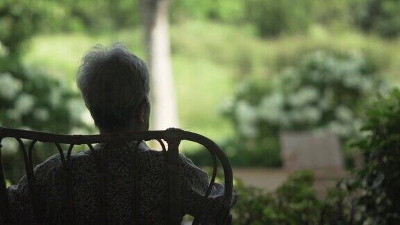 背后的老老人老年妇女坐在休息放松在天井看花园