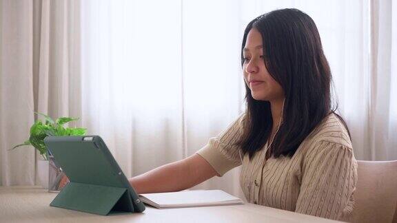 亚洲女孩向在家用平板电脑在线学习的老师打招呼