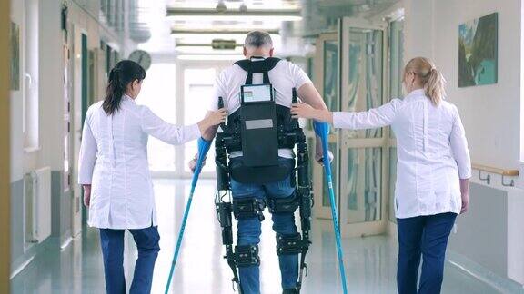 护士们正在帮助一名穿着防护服的残疾病人行走