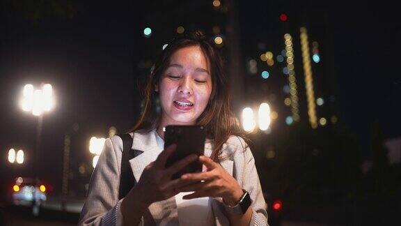 女性晚上在城市使用智能手机