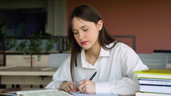 十几岁的女孩在图书馆做笔记准备考试回到学校