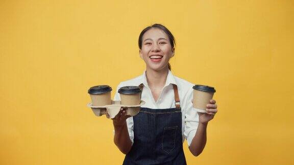 快乐微笑的亚洲女服务员正准备为顾客点菜同时看着隔离在黄色背景上的相机