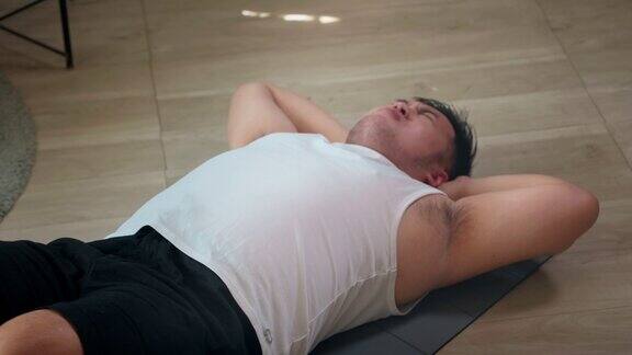特写一个胖乎乎的男人努力做仰卧起坐在家里减肥和燃烧脂肪卡路里的训练