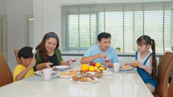 幸福的亚洲家庭在家里的餐桌上一起吃早餐