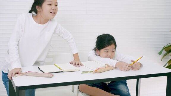 在中国语文课堂上一名亚裔年轻女教师正在教学和提问两名小学女生正试图举手回答问题年轻的亚洲女孩学习汉字和在黑板上写汉字