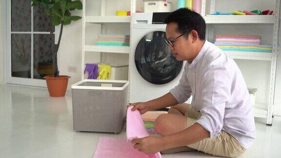 亚洲父亲是洗衣服和保持毛巾的男人家务帮手概念