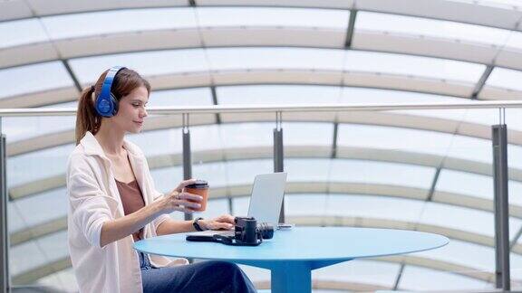 女商人在机场候机楼旅行时一边喝咖啡一边用笔记本电脑进行在线会议