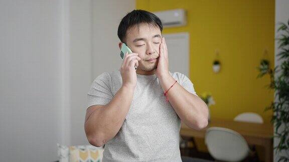 年轻的中国男子站在家里用智能手机聊天