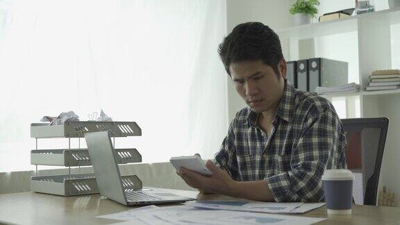 年轻的亚洲商人在家工作在笔记本电脑上计算财务图表数据核对财务文件投资和经营策略并总结成图表