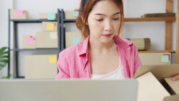 年轻的亚洲企业家女商人检查产品采购订单上的库存并保存到电脑笔记本电脑工作在家里的办公室