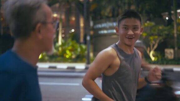 侧观亚洲华人活跃的老人和他的儿子晚上下班后一起在城市跑步慢跑