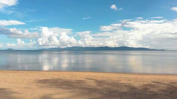 一架相机沿着棕榈树的海滩飞向海边的豪华度假胜地