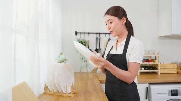 亚洲主动清洁服务女工清洁厨房和家庭美丽的年轻女孩管家清洁工感到高兴并擦拭盘子洗后的家务或家务