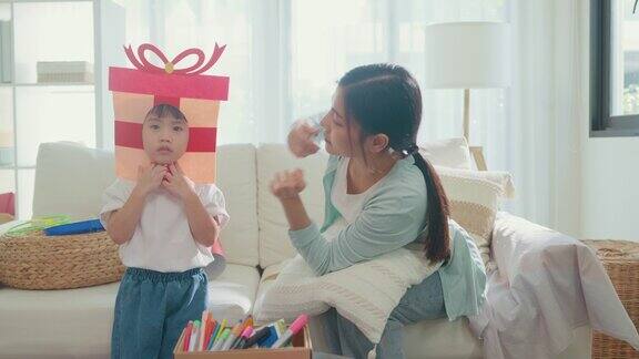 年轻的亚洲家庭妈妈和女儿在家里客厅的沙发上玩有趣的游戏家庭幸福时刻