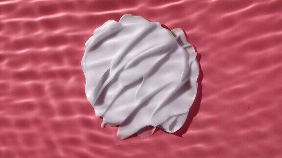 白色的奶油涂抹在粉红色的背景下荡漾的水