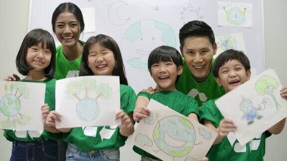 一组快乐的亚洲小学生身穿绿色生态t恤手持拯救世界计划的画纸志愿、自然、教育理念