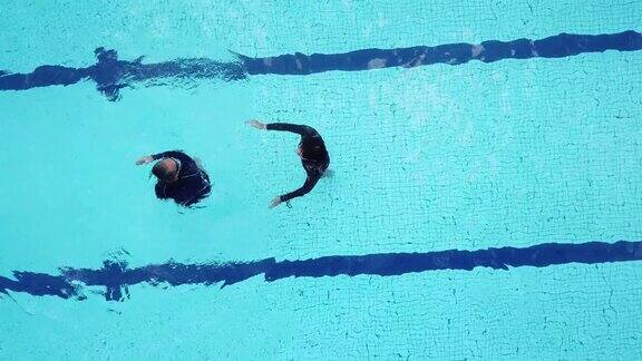无人机视角正上方游泳池教练指导他的高年级学生游泳技能