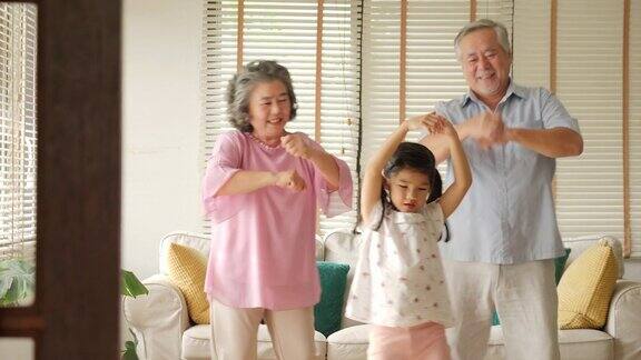 快乐的亚洲老年夫妇和他们的孙女在家里一起跳舞高级生活方式家庭理念