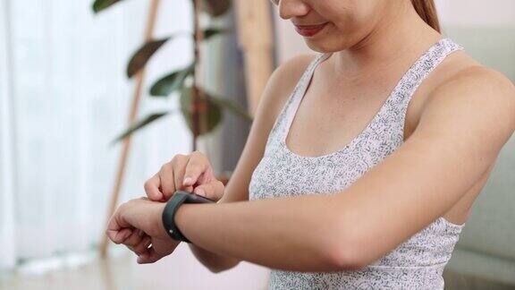 女性在家锻炼后调整智能手表