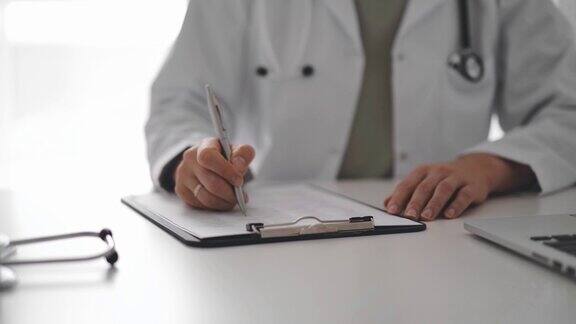 不知名的女医生坐在诊所或医院办公室的白色办公桌前写笔记近距离拍摄医学