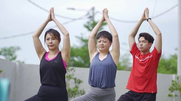 亚洲中国教练在后院指导女学生做树瑜伽