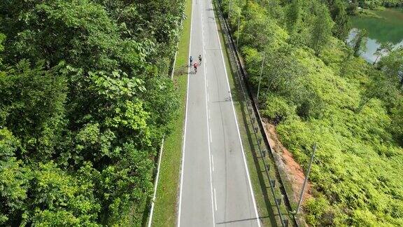 无人机视角下的亚洲华人男子自行车队周末上午骑行的乡村景象