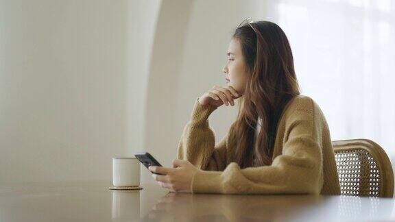 使用智能手机的年轻亚洲女性亚洲女性在家思考和孤独