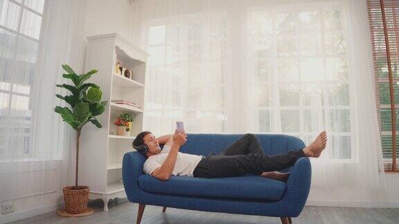 男人坐在沙发上用智能手机听音乐