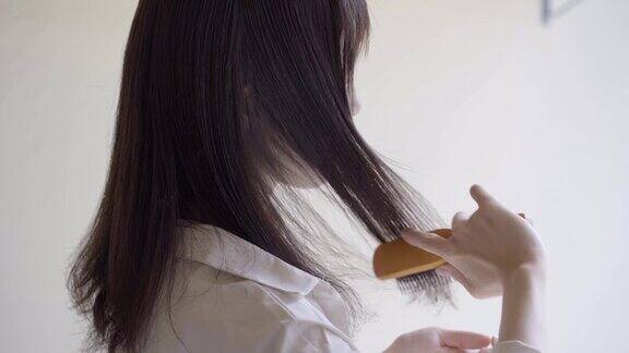 后视图的女人解开她的头发用刷子