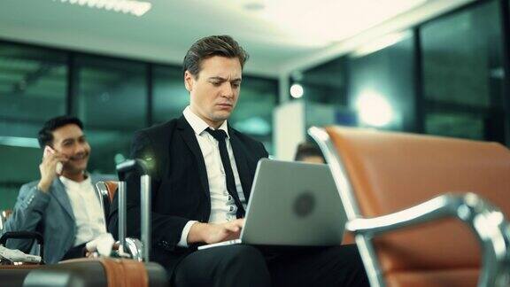 在机场候机楼一个忙碌的成年商人正在用笔记本电脑打字