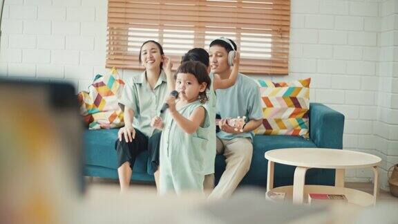 快乐的亚洲家庭在家里唱歌跳舞