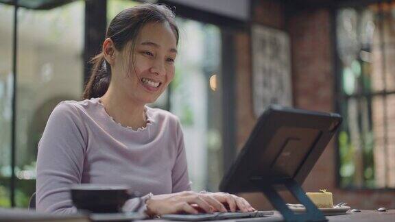 亚洲妇女在咖啡厅使用笔记本电脑