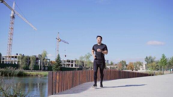 年轻的亚洲人在街上慢跑一个穿着运动服的帅气男人每天都在新鲜的空气中跑步
