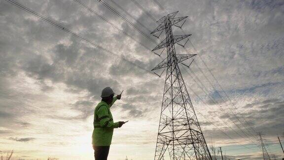 日落时分工程师利用无线电检查从高压输电塔发电来规划电站的工作