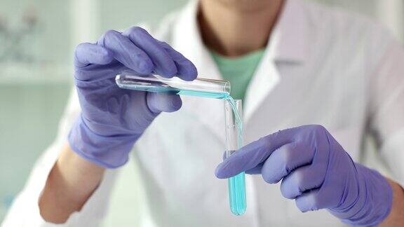 实验室工作人员手持玻璃试管倒入蓝色液体