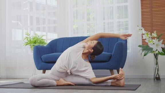 女性在家做伸展运动坐在垫子上的侧角姿势瑜伽锻炼