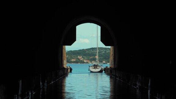 从潜艇军事隧道内部拍摄的美丽照片夏日里一艘白色的帆船停在外面旅游度假胜地