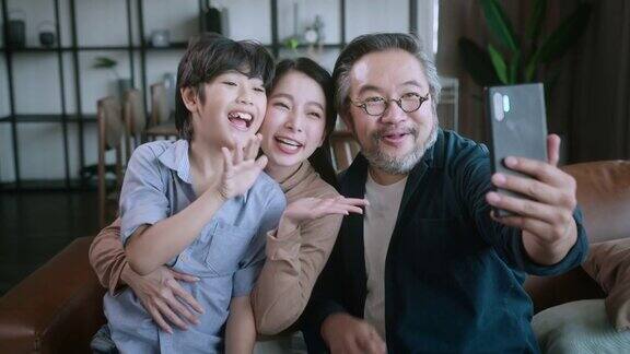 幸福甜蜜的亚洲家庭爸爸妈妈和儿子一起坐在沙发上视频呼叫爷爷奶奶笑着微笑的亚洲家庭在家里隔离隔离时刻处于封锁状态